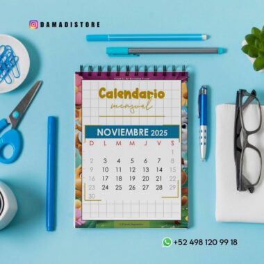 Un calendario manual encuadernado en espiral con fecha de noviembre de 2025 yace sobre una superficie azul, rodeado de material de oficina azul, una montura de gafas negra y una planta verde. El contacto de WhatsApp +52 498 120 99 18 es visible.