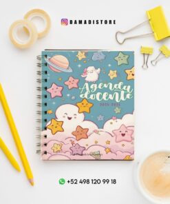 Una agenda colorida para profesor, con estrellas, nubes y un planeta en la portada, reposa sobre un escritorio blanco con lápices amarillos, clips, cinta adhesiva y una taza de café. También se ven los datos de contacto de Instagram y WhatsApp.