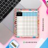 AGENDA DOCENTE PRIMARIA 2025-2026 ESTRELLAS 15 Un colorido cuaderno de tareas con cuadrícula reposa sobre el teclado de una laptop. Cerca hay un bolígrafo rosa, una calculadora y una regla. Se ven el perfil de Instagram y el contacto de WhatsApp de DAMADISTORE.