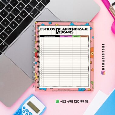 Un cuaderno espiral con una hoja de registro de estilos de aprendizaje en español se encuentra sobre un escritorio rosa, junto a una computadora portátil, una calculadora azul y un bolígrafo. La hoja tiene columnas etiquetadas como Visual, Auditiva y Kinestésica.
