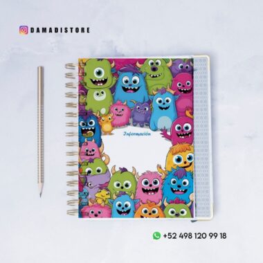 Un cuaderno de espiral con una cubierta colorida que representa monstruos sonrientes de dibujos animados, junto a un lápiz sobre una superficie blanca. El cuaderno dice "Información" en el centro. Se muestran las redes sociales y la información de contacto de WhatsApp.