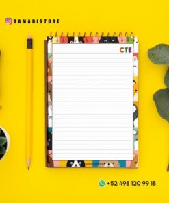 Un cuaderno de espiral con caras de animales en el borde, un lápiz amarillo, un sello de lacre, una pequeña suculenta en maceta y hojas verdes sobre fondo amarillo. El texto incluye el nombre de usuario de Instagram @damadistore y su número de WhatsApp.