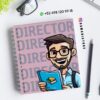 Cuaderno de espiral con una ilustración de dibujos animados de un hombre sonriente con un libro en la mano. En la portada se lee "DIRECTOR" en letras grandes. Cerca hay unas gafas, un bolígrafo y un número de teléfono con un icono de WhatsApp. Aparece la cuenta de Instagram @damadistore.