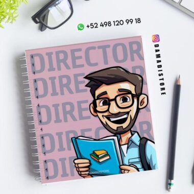 Cuaderno de espiral con una ilustración de dibujos animados de un hombre sonriente con un libro en la mano. En la portada se lee "DIRECTOR" en letras grandes. Cerca hay unas gafas, un bolígrafo y un número de teléfono con un icono de WhatsApp. Aparece la cuenta de Instagram @damadistore.