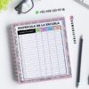 Un cuaderno de espiral con un formulario de matrícula de la Escuela, un lápiz negro, gafas y una planta sobre un escritorio blanco. En la parte superior se pueden ver los datos de contacto y la cuenta de Instagram @damadistore.