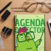 Un cuaderno de espiral con un pájaro verde de dibujos animados y el texto "Director de Agenda" en la portada descansa sobre un escritorio con un teléfono, gafas, bolígrafo, clips, goma de borrar, regla e información de contacto de DAMADISTORE.