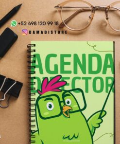 Un cuaderno de espiral con un pájaro verde de dibujos animados y el texto "Director de Agenda" en la portada descansa sobre un escritorio con un teléfono, gafas, bolígrafo, clips, goma de borrar, regla e información de contacto de DAMADISTORE.