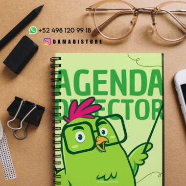 Un cuaderno de espiral con un pájaro verde de dibujos animados y el texto "Director de Agenda" en la portada descansa sobre un escritorio con un teléfono, gafas, bolígrafo, clips, goma de borrar, regla e información de contacto de DAMADISTORE.