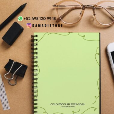 Un cuaderno de espiral con la cubierta verde y la etiqueta "Ciclo Escolar 2025-2026" descansa sobre un escritorio marrón junto a unas gafas, un bolígrafo negro, gomas de borrar, clips y una regla. Encima del cuaderno hay información de contacto y direcciones de redes sociales.
