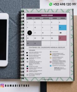 Una agenda encuadernada en espiral abierta hasta marzo de 2026 muestra un calendario mensual con fechas destacadas, una clave para eventos escolares, información de contacto y parte de un smartphone cerca, sobre un escritorio.