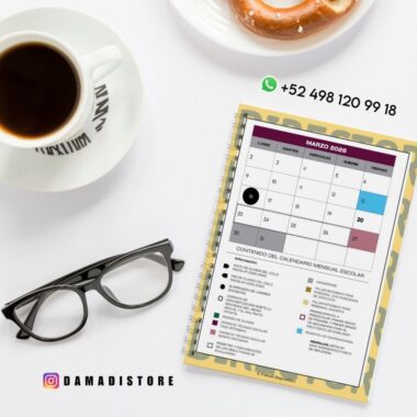 Una taza de café, unas gafas y un donut junto a un calendario escolar de marzo de 2026 encuadernado en espiral con eventos codificados por colores, un número de contacto de WhatsApp y el usuario de Instagram @DAMADISTORE.