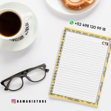 Un cuaderno de espiral con páginas rayadas con la etiqueta "CTE" descansa sobre un escritorio blanco junto a unas gafas negras, una taza de café, un donut y datos de contacto. La cuenta de Instagram @DAMADISTORE está visible.