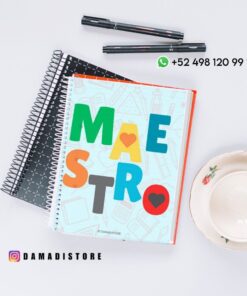 Un cuaderno de colores con "MAESTRO" en la portada descansa sobre dos cuadernos negros de espiral, junto a dos bolígrafos negros y una taza de té con platillo. Los datos de contacto y la cuenta de Instagram aparecen sobre una superficie blanca.