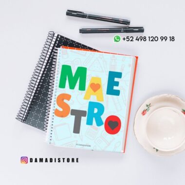 Un cuaderno de colores con "MAESTRO" en la portada descansa sobre dos cuadernos negros de espiral, junto a dos bolígrafos negros y una taza de té con platillo. Los datos de contacto y la cuenta de Instagram aparecen sobre una superficie blanca.
