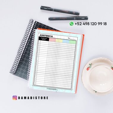 Vista superior de un escritorio con un cuaderno de espiral, una hoja titulada "ASISTENCIA", bolígrafos, una taza de té con un platillo e información de contacto de DAMADISTORE con iconos de WhatsApp e Instagram.
