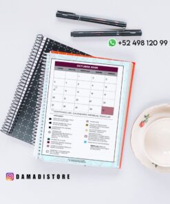 Un cuaderno de espiral abierto en la página de un calendario de octubre de 2025 está sobre un escritorio blanco junto a dos bolígrafos y una taza de té floral con un platillo. Se ven los datos de contacto de WhatsApp y la cuenta de Instagram @damadistore.