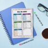 Agenda docente primaria ajolote 2025-2026 13 Un cuaderno con el horario de limpieza, con secciones de colores para los diferentes turnos, colocado encima de un cuaderno azul. Cerca hay gafas, un bolígrafo y una taza de café. Los datos de contacto y las redes sociales están a la vista.