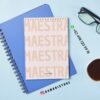 Agenda docente primaria ajolote 2025-2026 21 Encima de un cuaderno azul hay un bloc de notas en espiral con la palabra