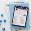 Agenda docente primaria niño 2025-2026 9 Un calendario encuadernado en espiral de febrero de 2026 está colocado sobre un cuaderno azul, con papeles arrugados azules cerca. Arriba hay un número de contacto de WhatsApp: +52 498 120 99 18, y más abajo el usuario de Instagram @damadistore.