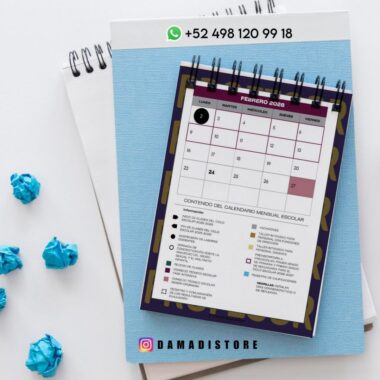 Un calendario encuadernado en espiral de febrero de 2026 está colocado sobre un cuaderno azul, con papeles arrugados azules cerca. Arriba hay un número de contacto de WhatsApp: +52 498 120 99 18, y más abajo el usuario de Instagram @damadistore.