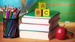 Una colorida exhibición de útiles educativos, que incluye una pila de libros, un vaso con lápices de colores, bloques alfabéticos que deletrean "abc" y una manzana roja al lado de un globo terráqueo, que simboliza un ambiente de aprendizaje para el Plan Semestral Proyectos Institucionales II.